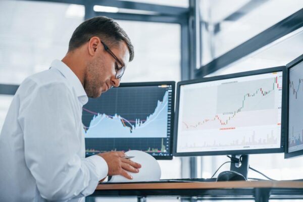 複数のモニターで株価をチェックする男性